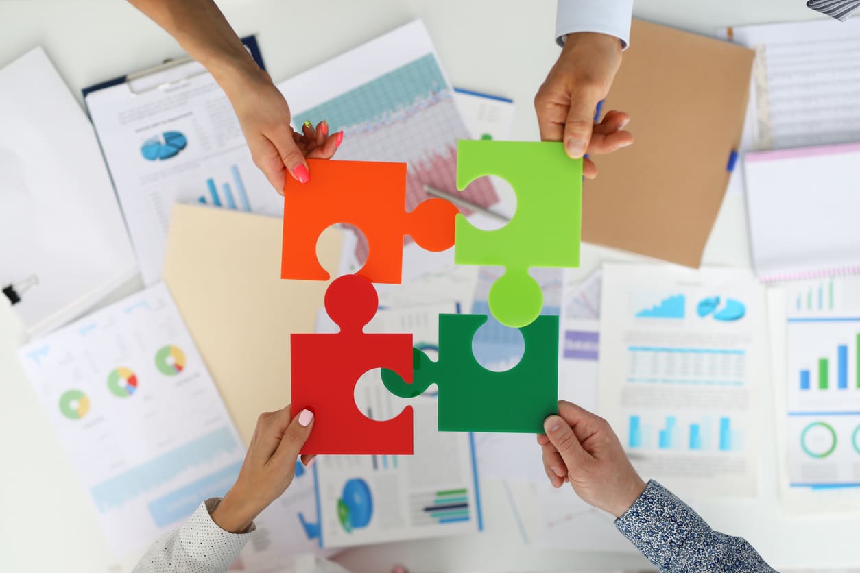 Employees in office hold colorful puzzles and put them together
